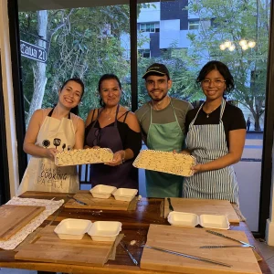 Friends smiling with trays of handmade pasta after Luciana's class